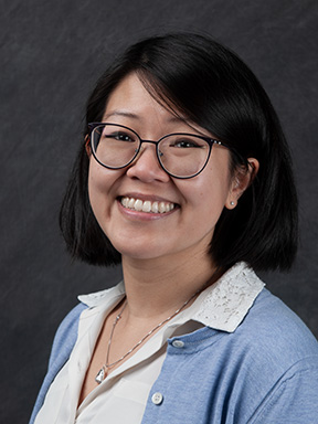 Headshot of bespectacled woman with short black hair, a white blouse and periwinkle cardigan.