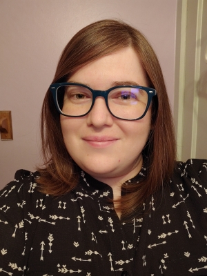 female, brown hair, glasses, wearing a black top