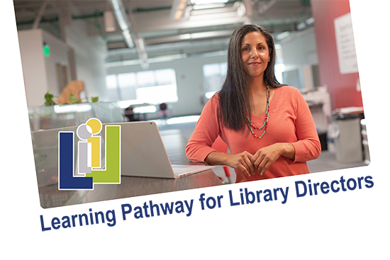 A woman stands next to bookshelves in her library building.