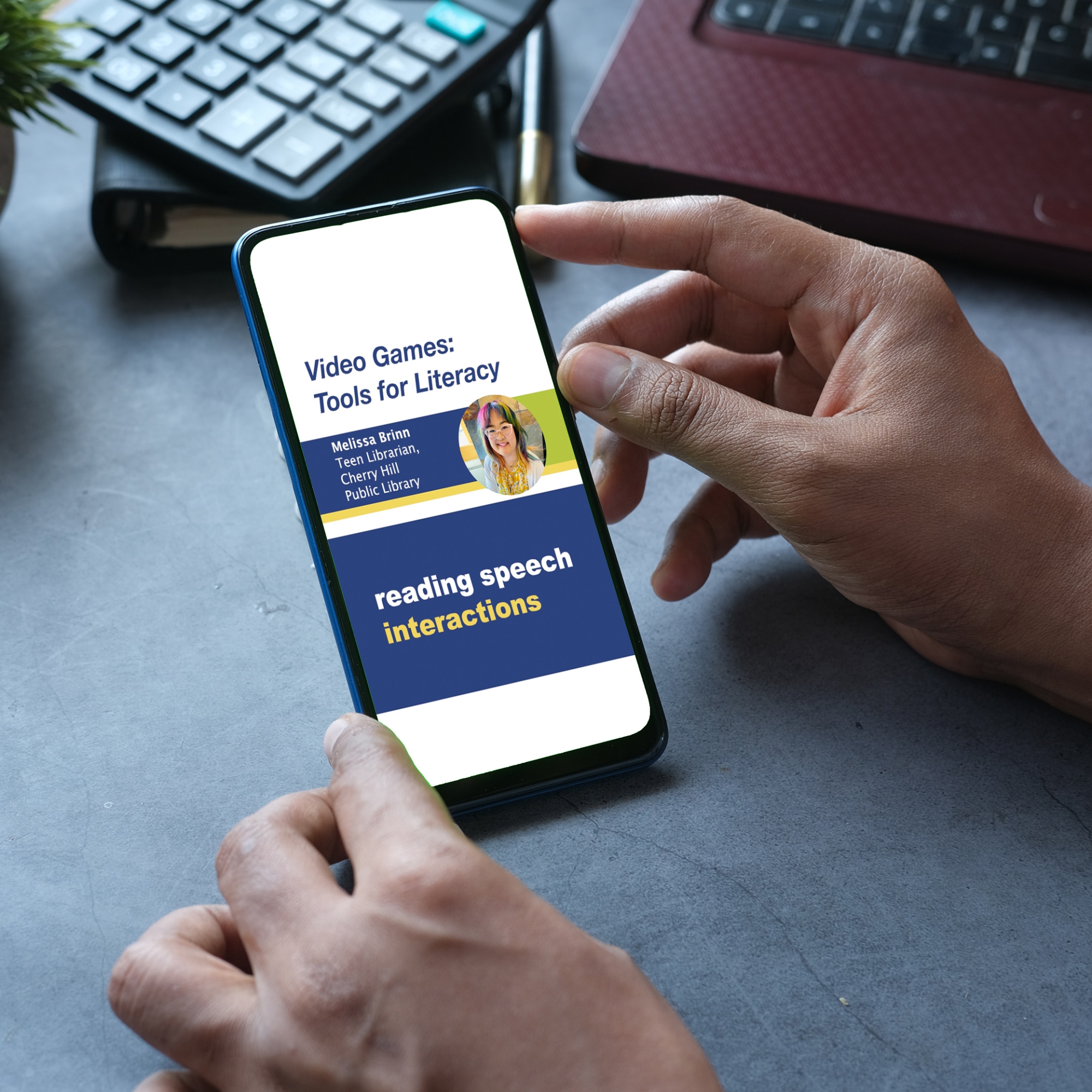 A person holds a smartphone as a clip is displayed from the webinar Video Games: Tools for Literacy with presenter Melissa Brinn.