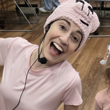 A female librarian wearing all pink with a Piggie hat and microphone
