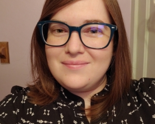 female, brown hair, glasses, wearing a black top