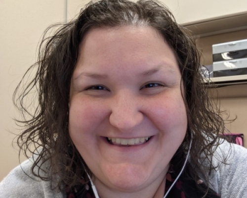 young Caucasian woman with shoulder length curly hair, smiling