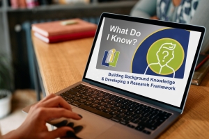 A person sits at a laptop, the screen displays the title of the module. It reads: What Do I Know? Building Background Knowledge and Developing a Research Framework