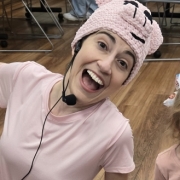 A female librarian wearing all pink with a Piggie hat and microphone