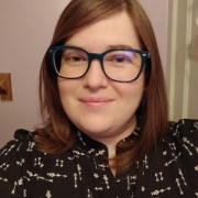 female, brown hair, glasses, wearing a black top